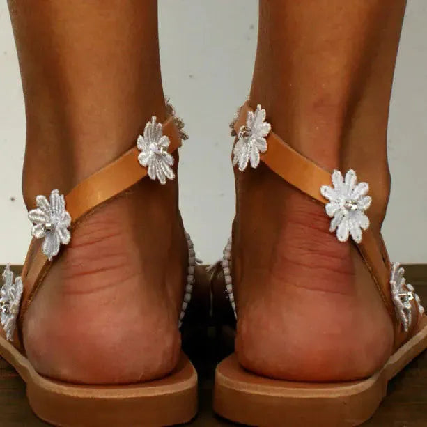 Brown ladies flat sandals with flower decoration and a rubber sole.