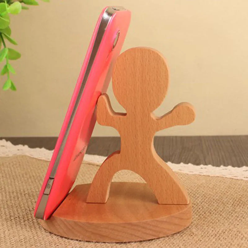 Solid beech wood phone stand with a decorative resin puppy figurine, holding a mobile phone at an angle with a charging cable threaded through the back.