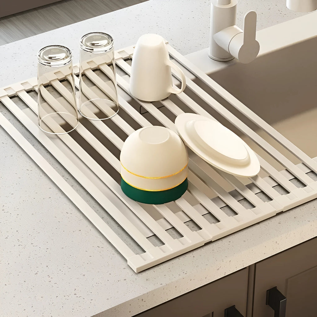 Milky White foldable stainless steel kitchen draining rack shown beside a sink, demonstrating its tri-fold mechanism.