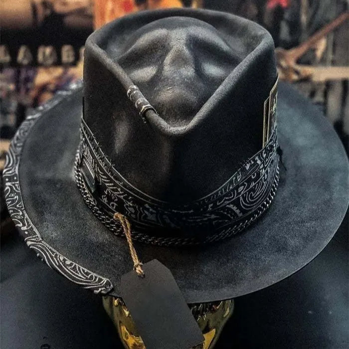 Handmade black wool felt skull hat with a pointed conical crown on a plain background.