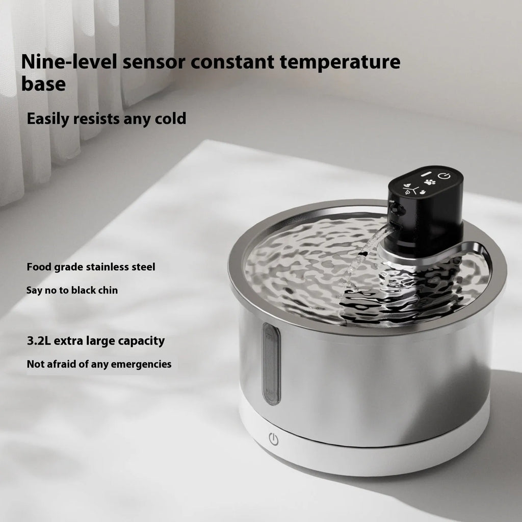 White stainless steel cat water fountain with constant temperature heating base on a table.