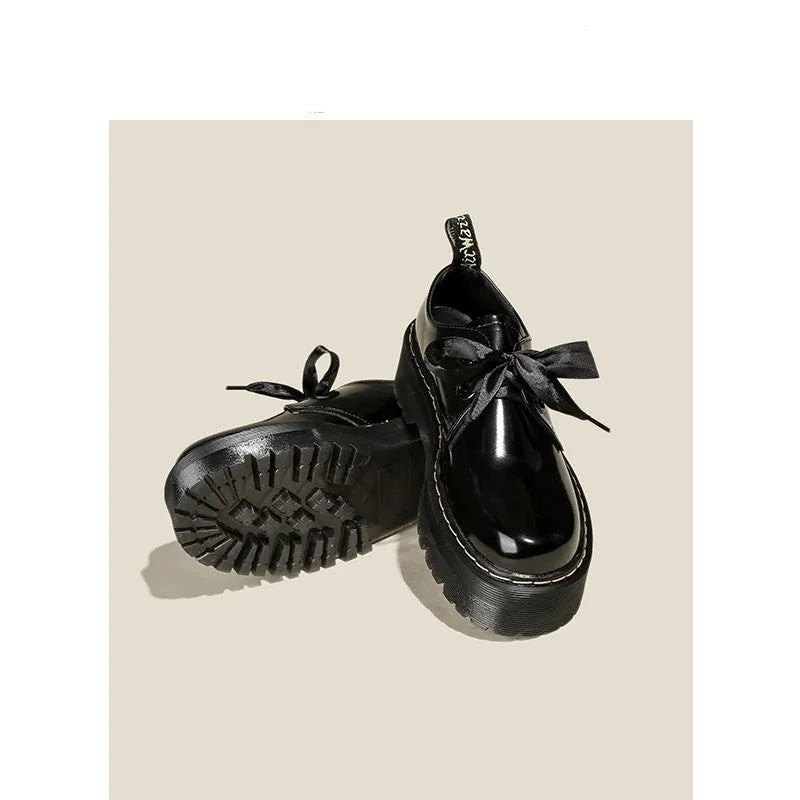 Women's black leather shoes with a thick sole, cross strap, and lace-up closure.