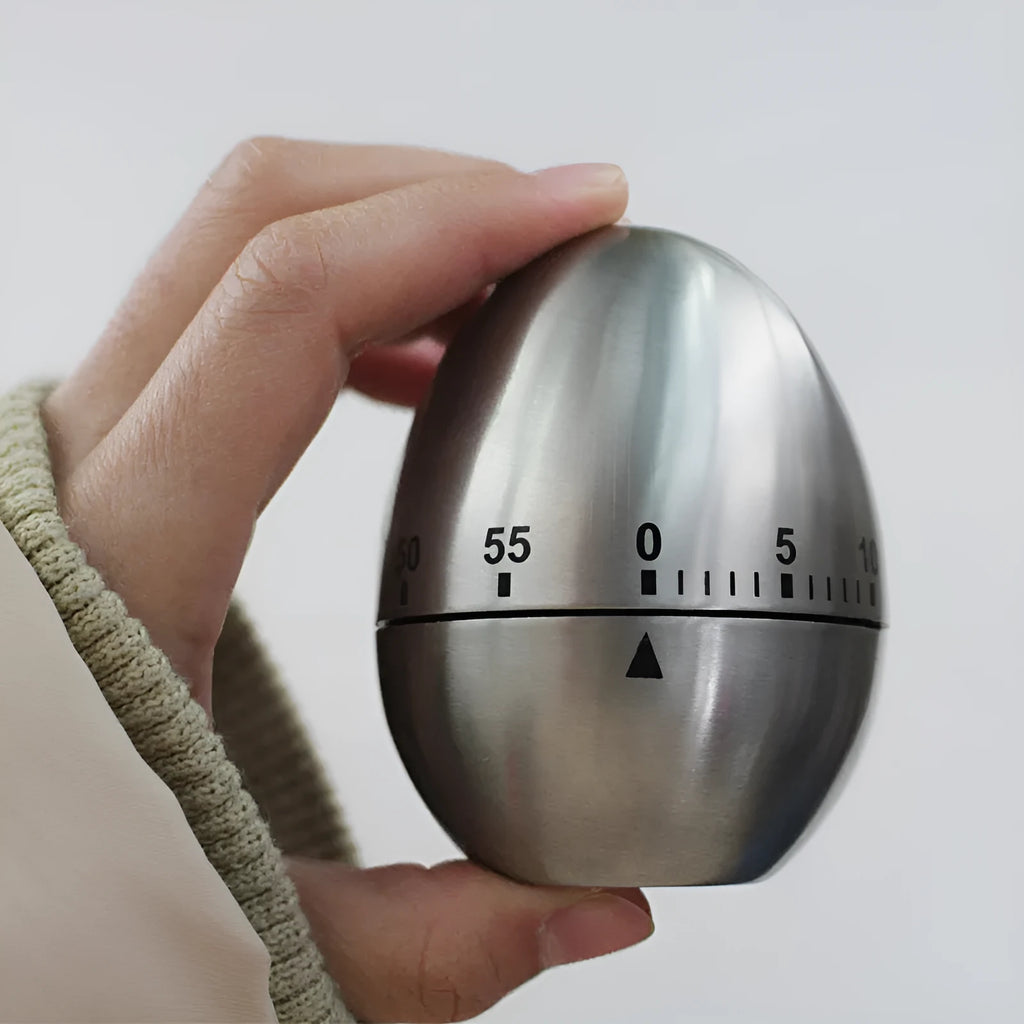 Stainless steel egg-shaped mechanical kitchen timer on countertop