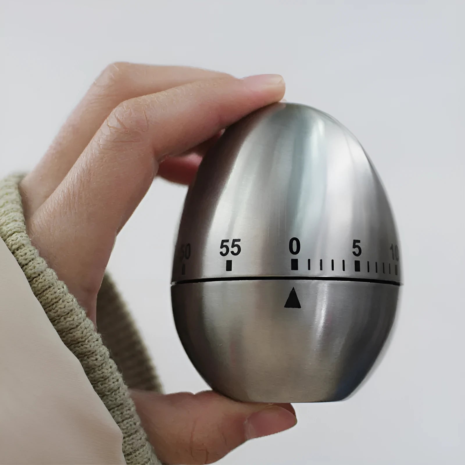 Stainless steel egg-shaped mechanical kitchen timer on countertop