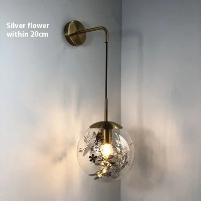 Modern creative wall-mounted bedside lamp with a golden flower glass shade and warm LED light.