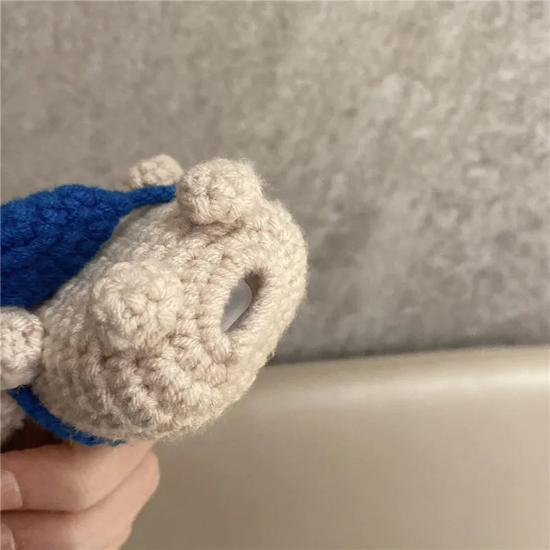 Handmade knitted AirPods case shaped like a backpack with koala ears on a blue background.