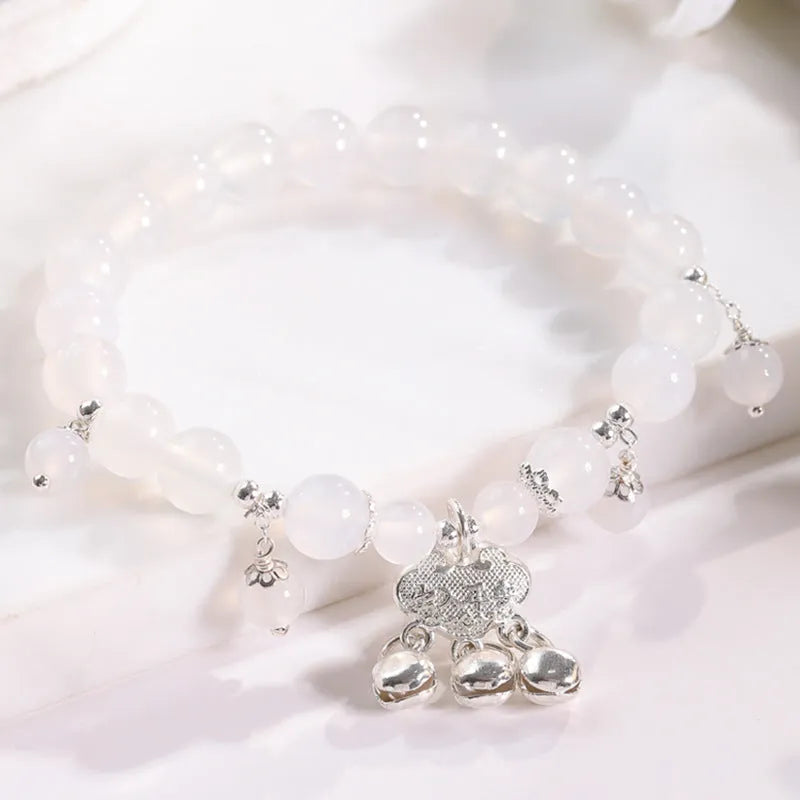 Close-up of a women's opal cat's eye stone beaded bracelet with diamond-shaped beads on a wrist.