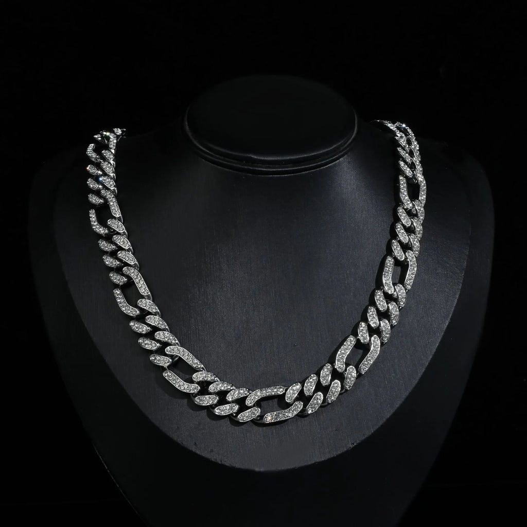 Rap style figaro chain necklace with geometric rhinestone pendant in silver colour on a plain background