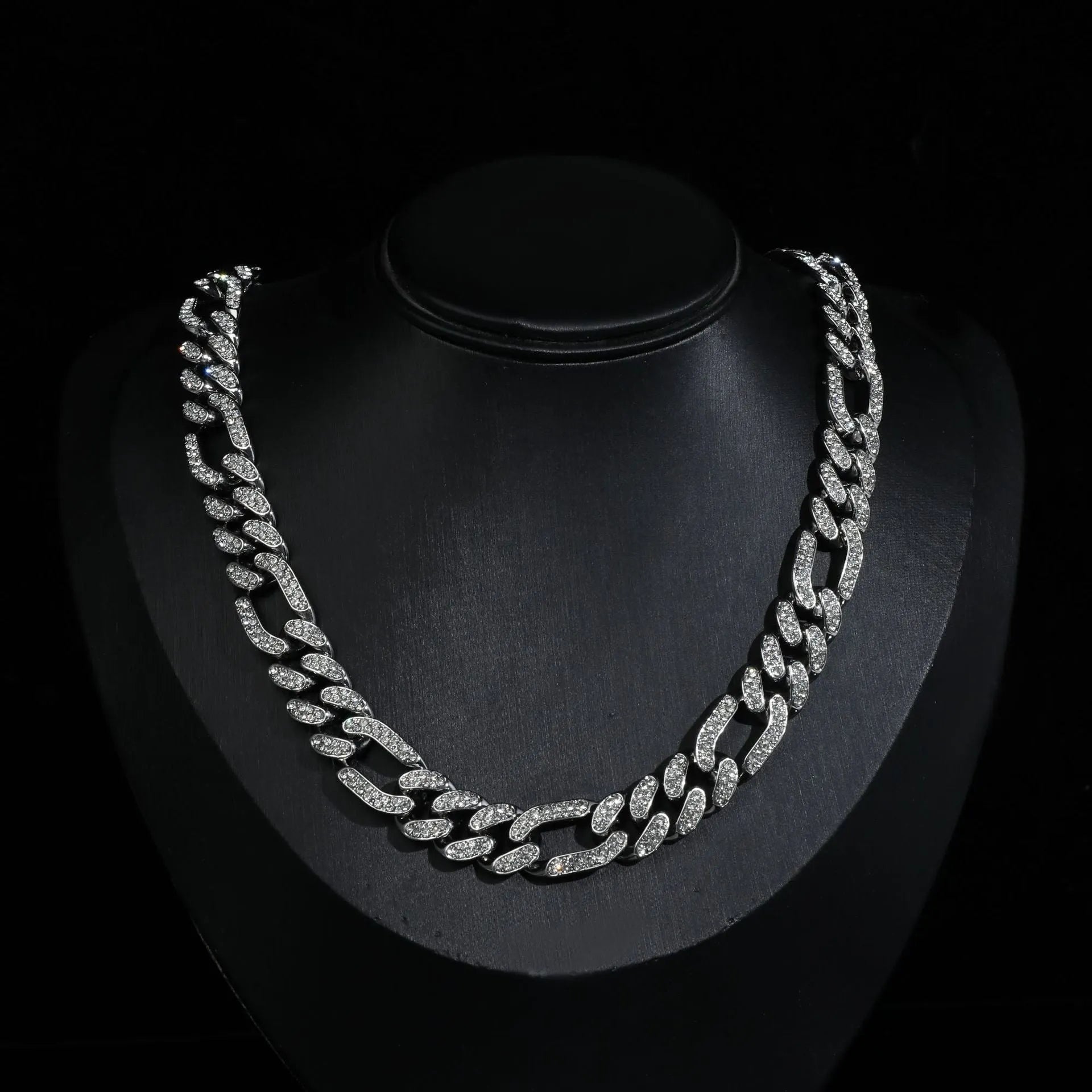 Rap style figaro chain necklace with geometric rhinestone pendant in silver colour on a plain background