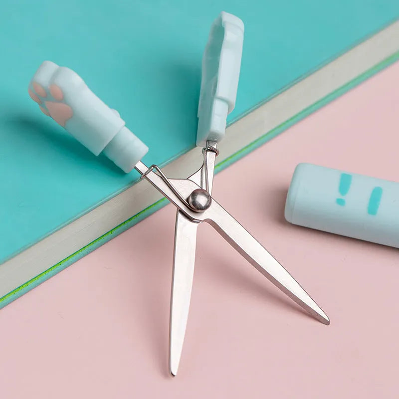 A folded cat paw design scissors in blue, showing compact size and pen-type mechanism.