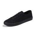 All black women's low-top canvas flat shoes with flat rubber sole and lace-up front.
