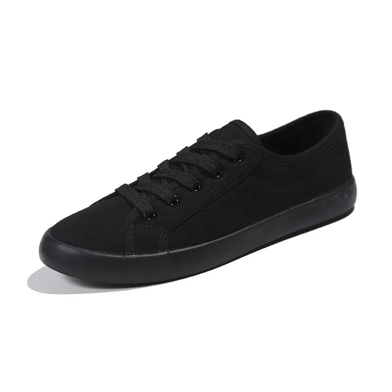All black women's low-top canvas flat shoes with flat rubber sole and lace-up front.