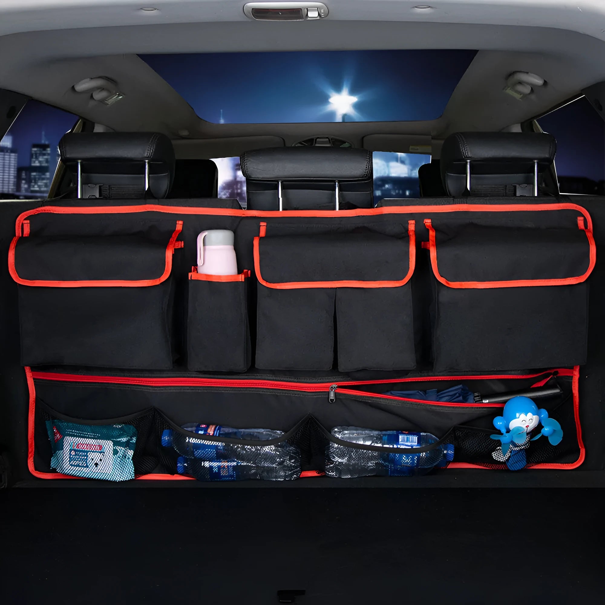 Car trunk hanging storage shopping bag in black with red piping, showing Oxford cloth construction and reinforced handle