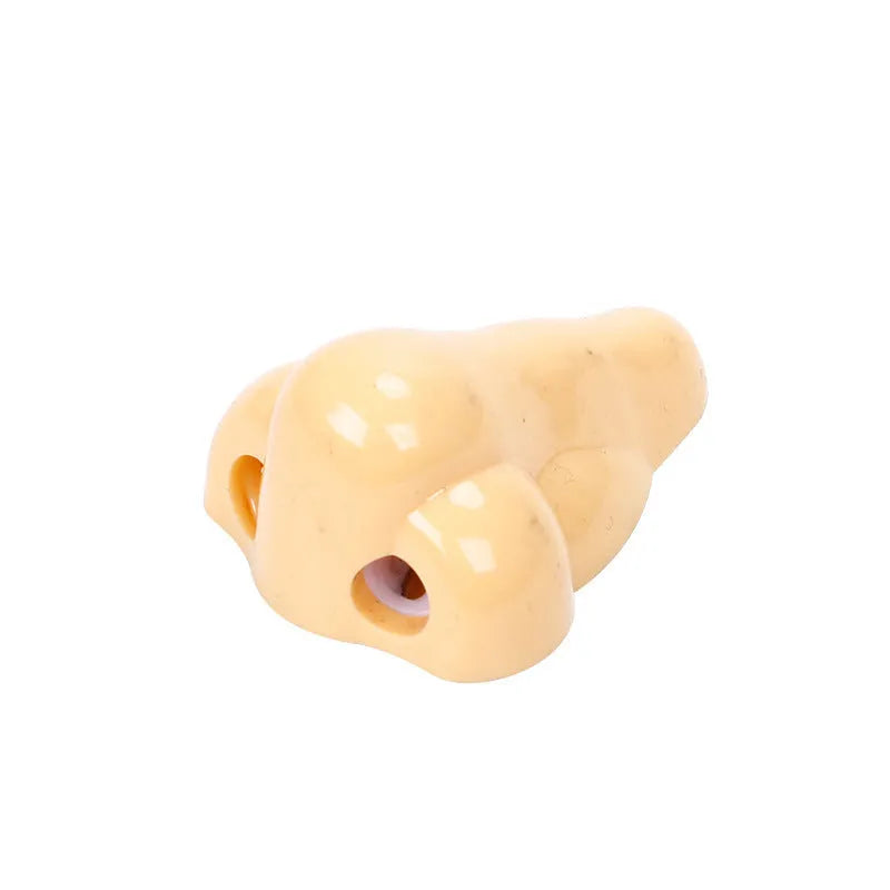 Flesh-coloured plastic pencil sharpener with large nostril and geometric shape on a white background.