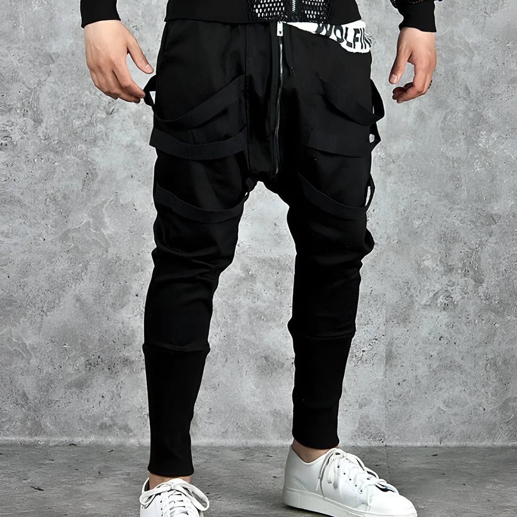 Men's black low crotch cross trousers with tapered cone leg and small hem on a plain background