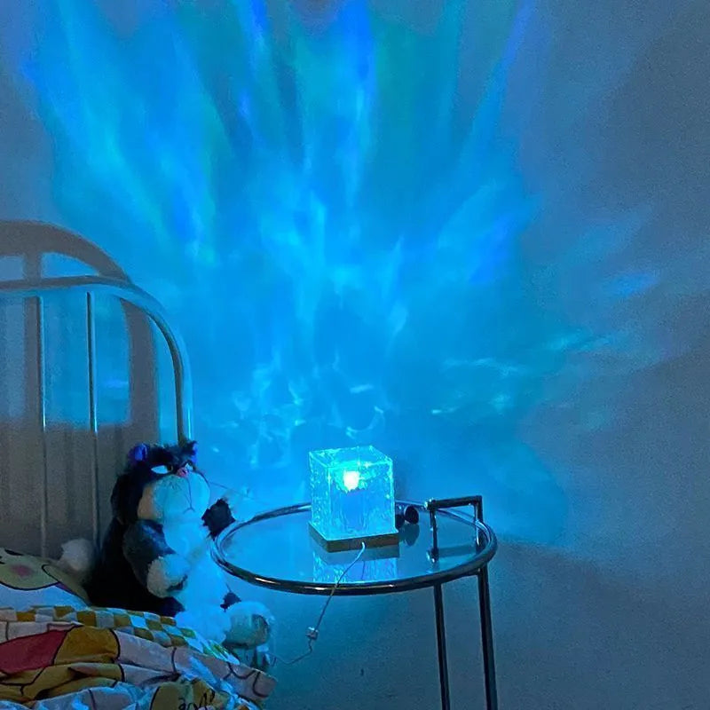 Modern geometric crystal table lamp projecting blue water ripple light pattern on a wall.