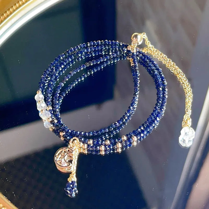 Close-up of a women's multi-layer blue sand bracelet with a three-ring design and gold sand stone cut.
