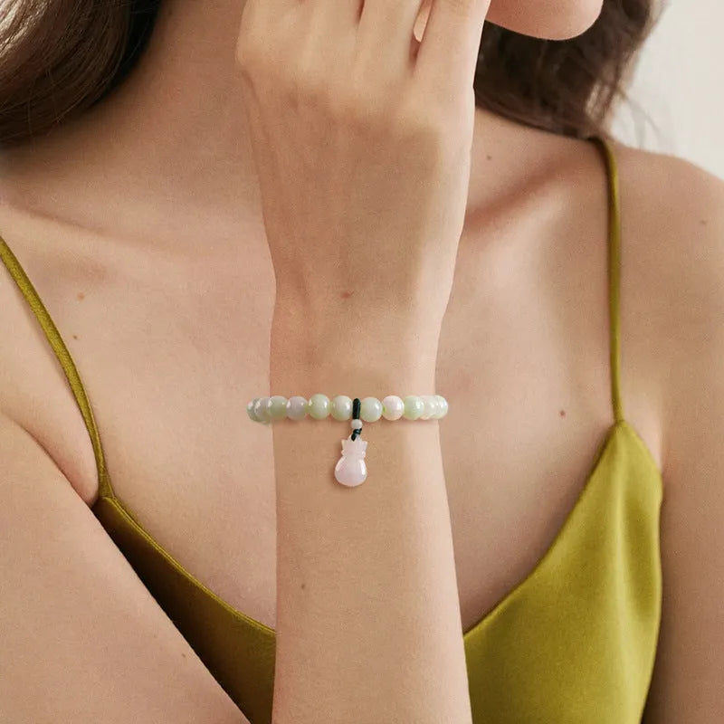 Close-up of an 8mm floral carved jade bracelet on a wrist.