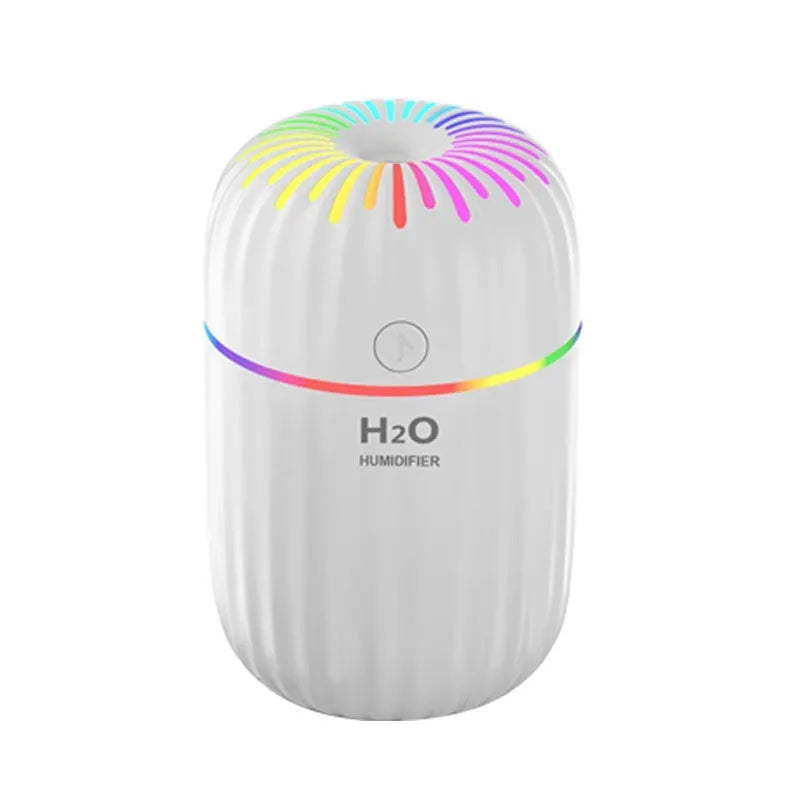 Small white USB desktop humidifier with water tank on a wooden desk.