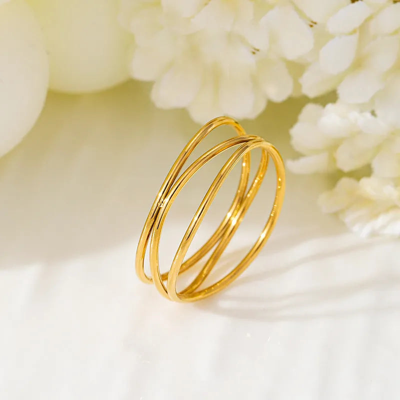 Gold titanium steel geometric ring with a three-layer coil design on a plain background.