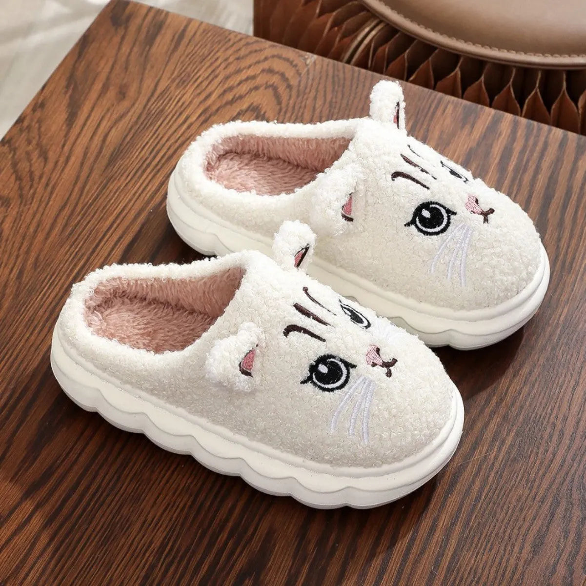 Pair of pink winter cartoon cat fluffy slippers on floor, non-slip EVA sole