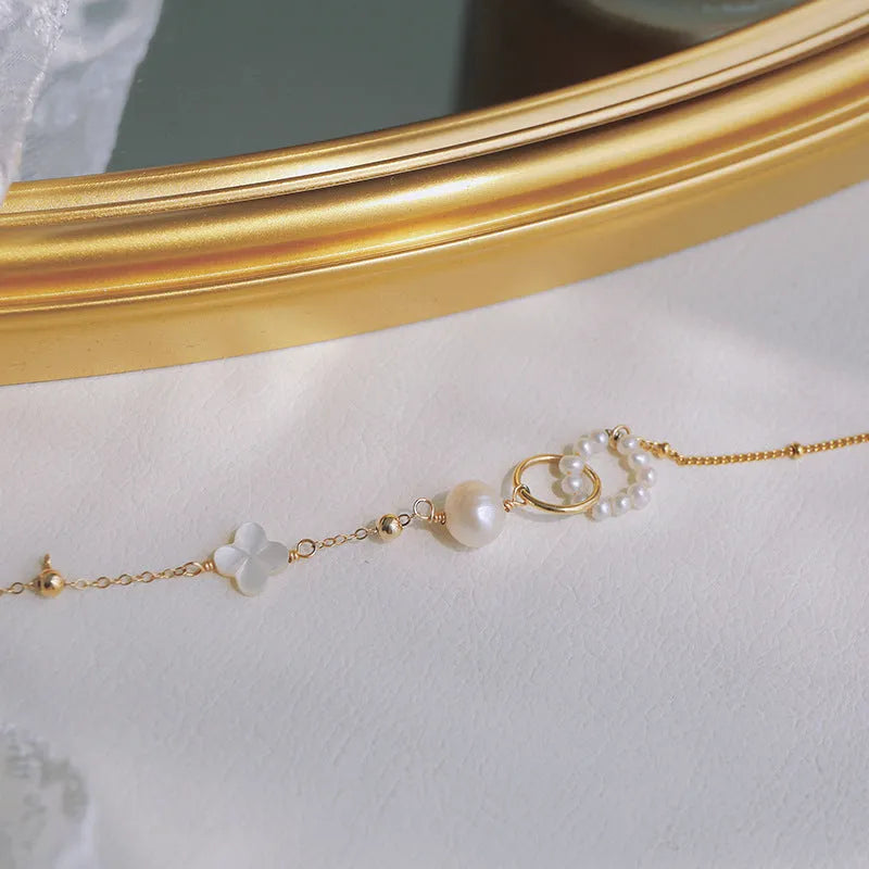 Women's natural freshwater pearl bracelet with gold-plated clasp and floral charm accents on a white background.