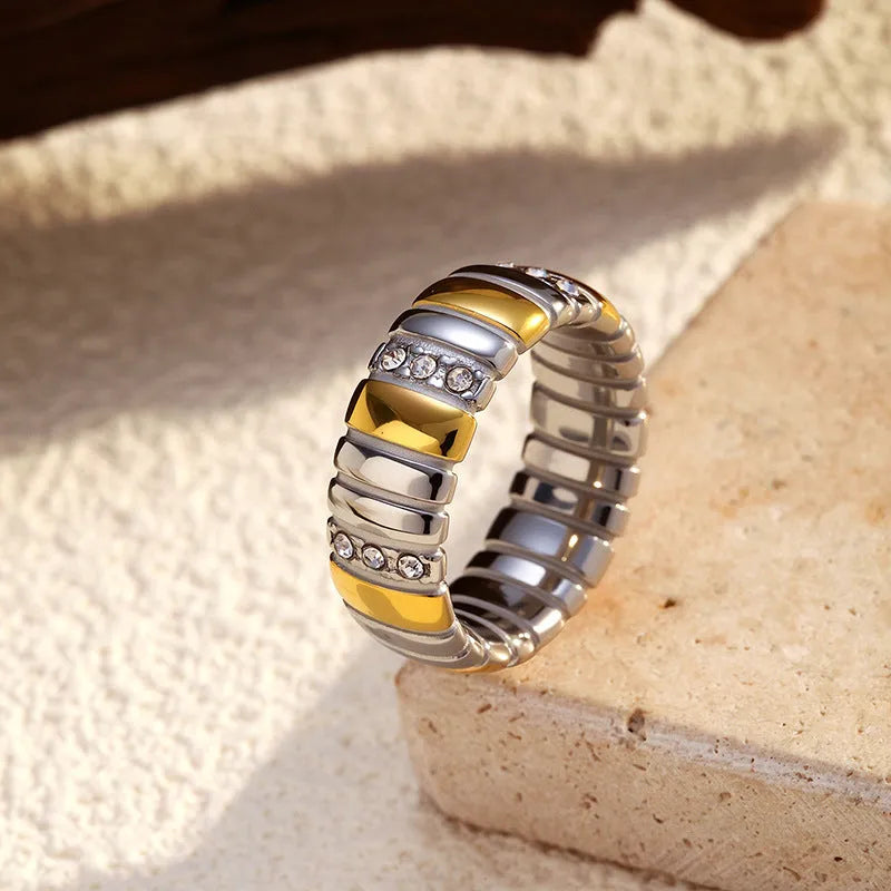 Gold and silver two-tone geometric cross stainless steel ring on a light background showing texture and electroplated finish
