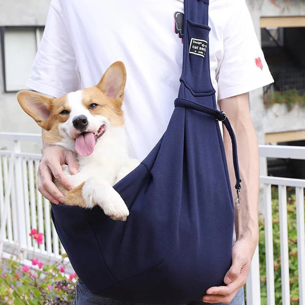 Light grey polyester pet sling carrier with cell phone pocket, worn around waist, holding a small dog
