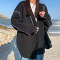 Women's loose fit black knitted cardigan coat with long sleeves on a hanger