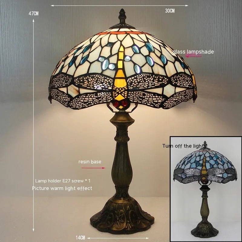 Tiffany-style stone table lamp with blue dragonfly design on a wooden surface.