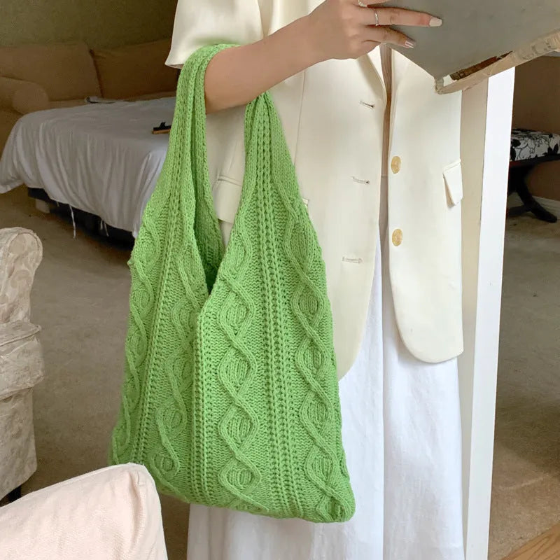 Women's white hollow knitted crochet tote bag with double shoulder straps, shown on a table.