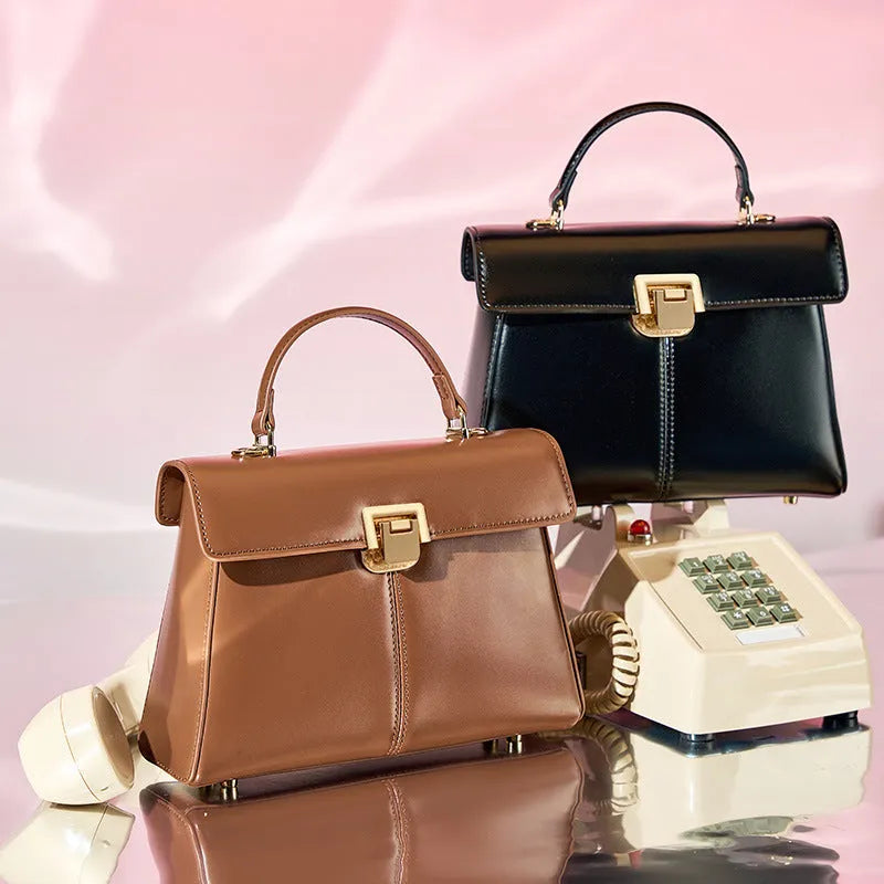 Black genuine leather women's shoulder bag with a clasp closure and long adjustable strap.