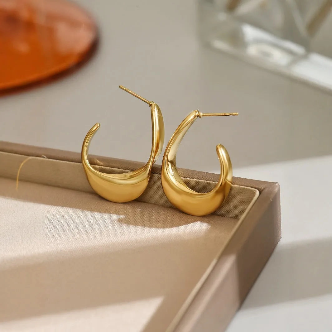 Geometric gold earrings with ring shape on stainless steel post-back closure against white background
