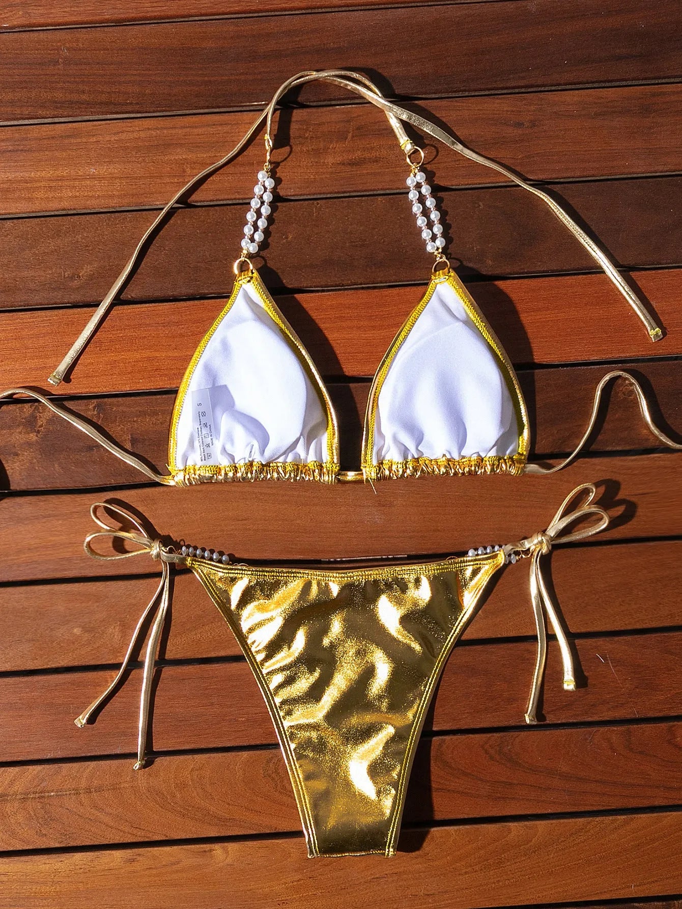 Gold women's halter bikini with front lace-up tie and decorative pearl chain detail.