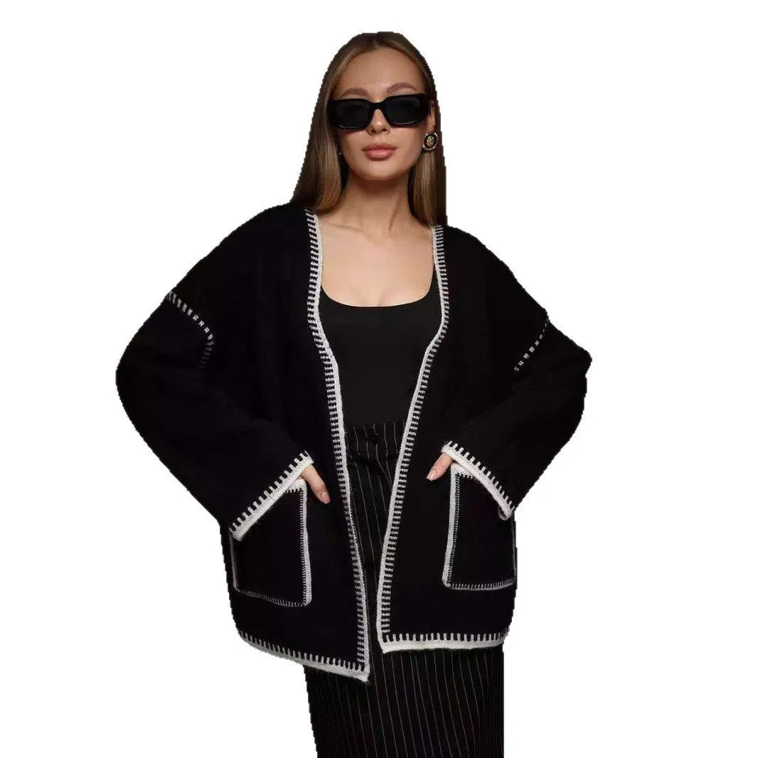 Loose beige knitted cardigan with a lace-up front, worn open over a white top.