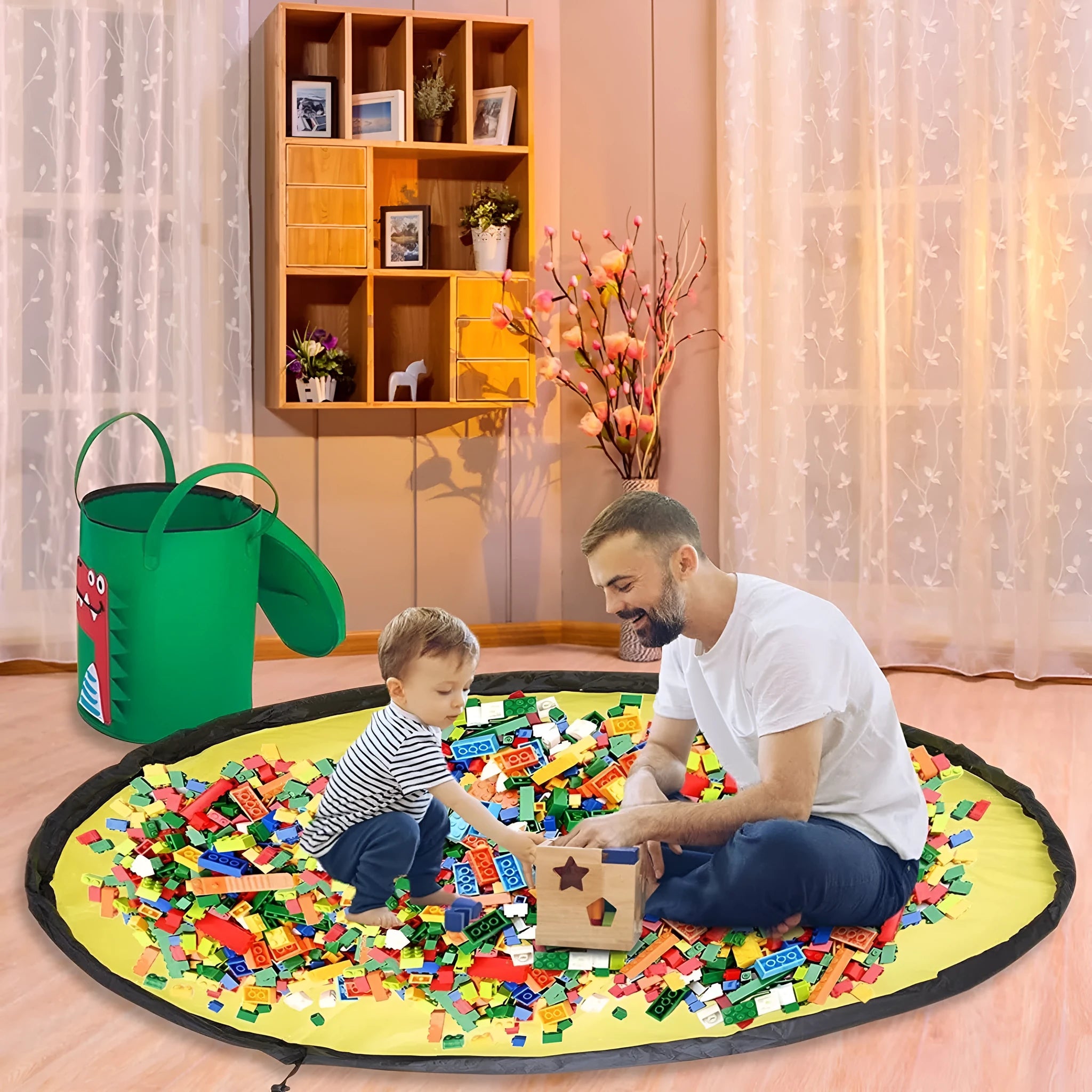Green felt cube storage bag with pull rope, laid flat as a play mat next to toys.