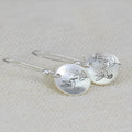 Silver round women's earrings with engraved bird and floral designs in glossy finish