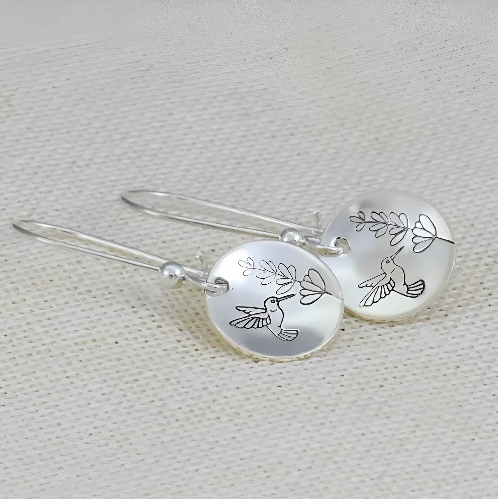 Silver round women's earrings with engraved bird and floral designs in glossy finish