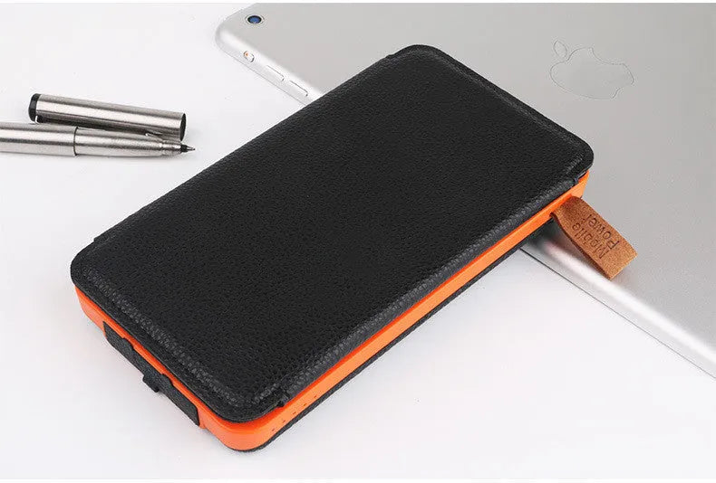 Black outdoor solar power bank with a solar panel, LED light, and soft leather finish, shown with a charging cable.
