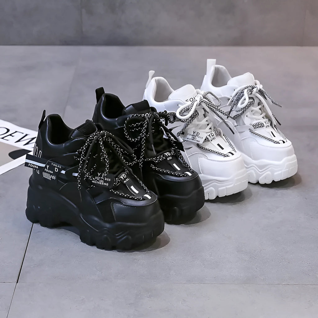 Women's white and black platform sports shoes with cross strap and rubber sole.