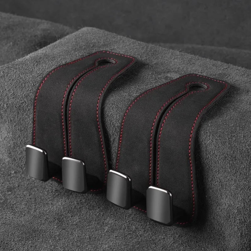 Black car seat hook with suede padding and flip-back design mounted on a grey car seat