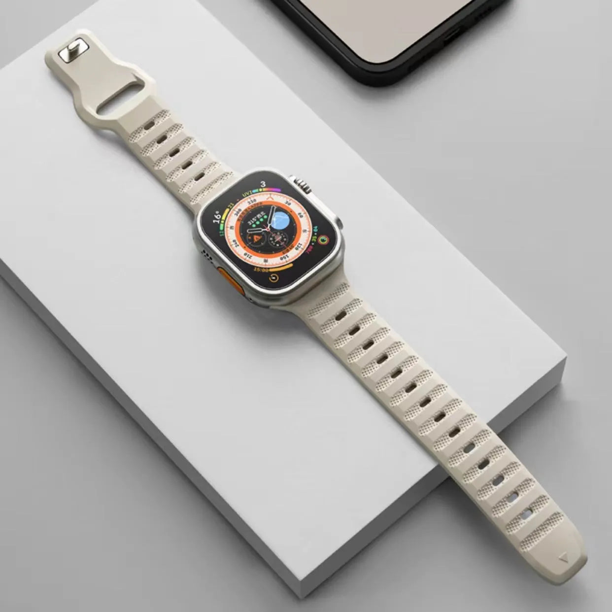 Black fluoro rubber Apple Watch strap with T-buckle closure shown detached from watch.