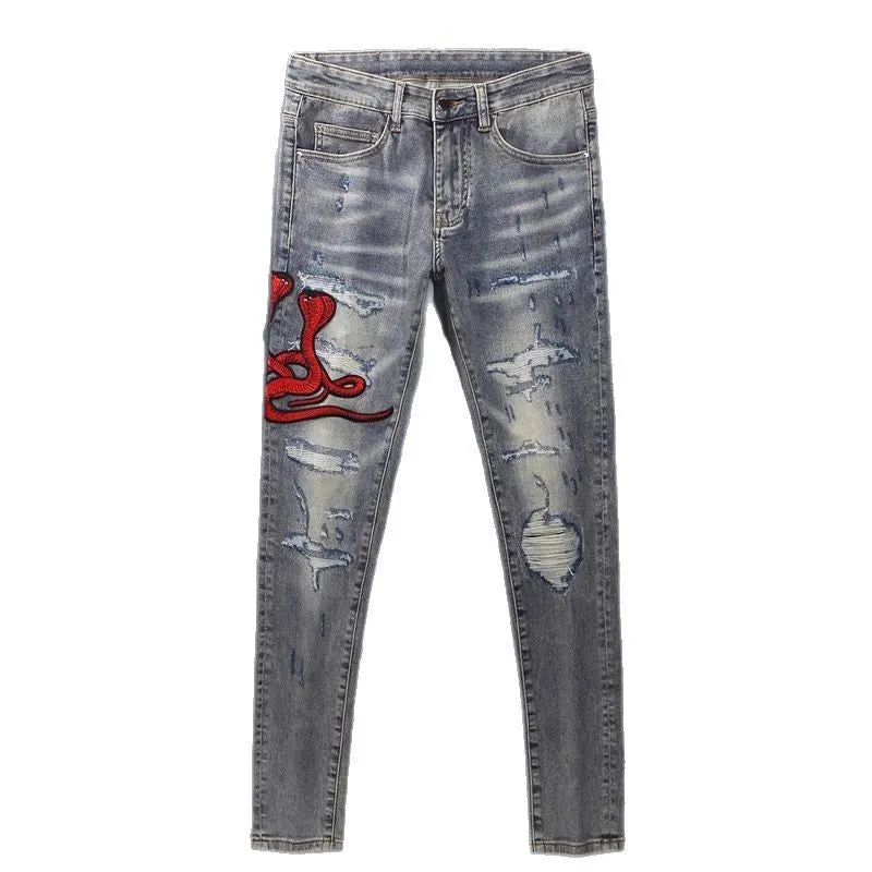 Man wearing slim-fit light blue jeans with distressed knee patches and embroidered back pocket detail.