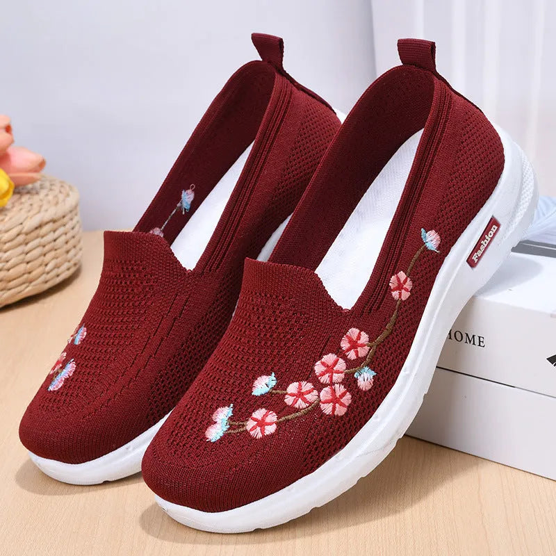 Women's embroidered floral flat pump in woven fabric with a low heel and round toe.