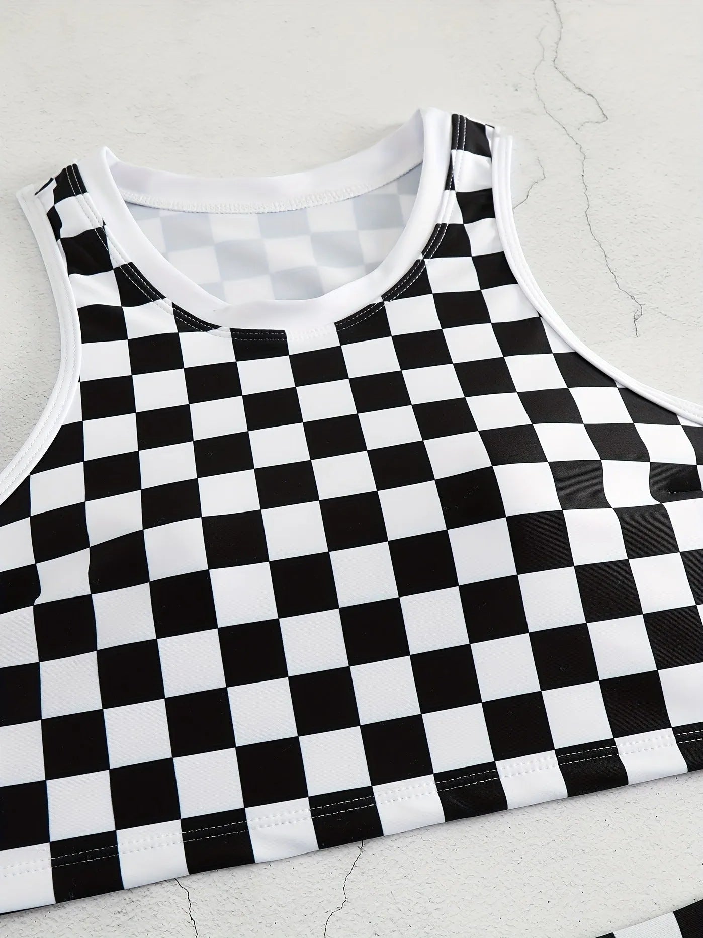 Women's black and white checkerboard racing one-piece swimsuit with backless design and suspender straps