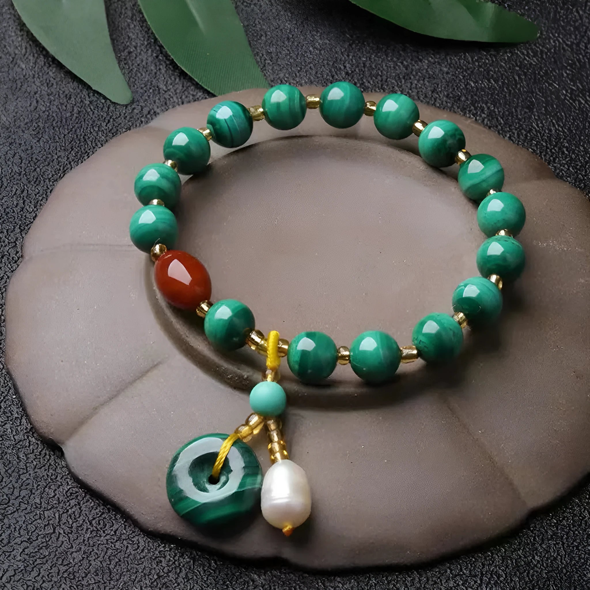 Close-up of a natural malachite and red agate bracelet with 7-8mm barrel beads on a wrist.