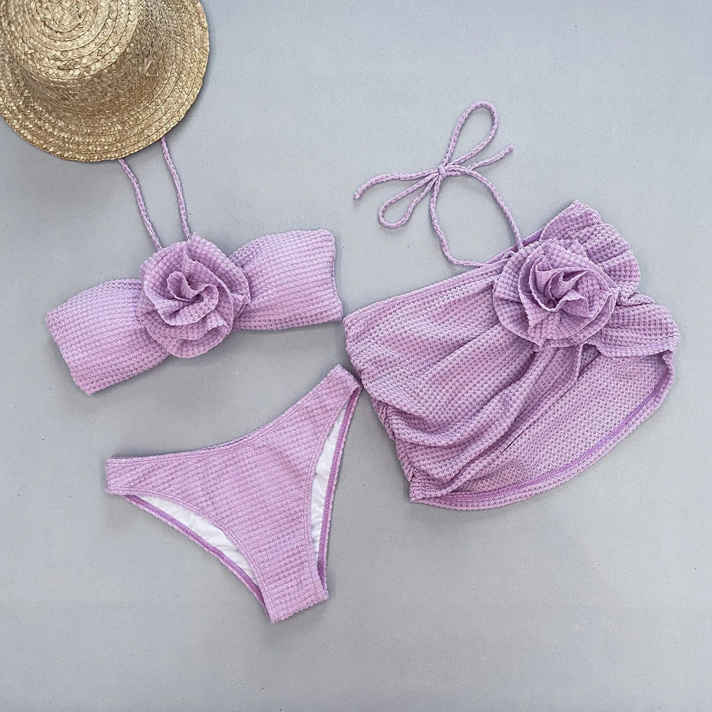 Women's white 3D flower split three-piece bikini swimsuit set with bra, briefs, and skirt on a mannequin.