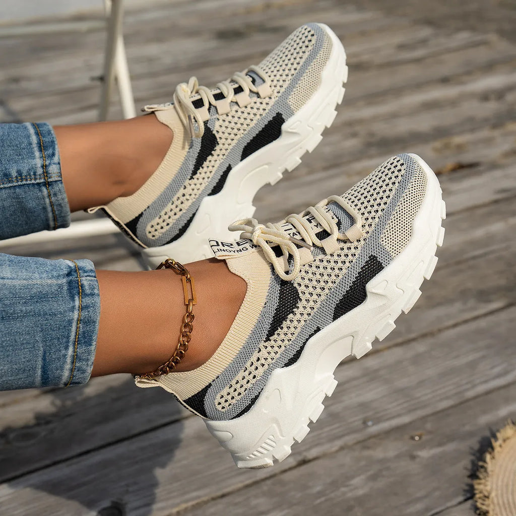 Women's Flyknit mesh lace-up sneakers in grey and white colour combination on a flat rubber sole.