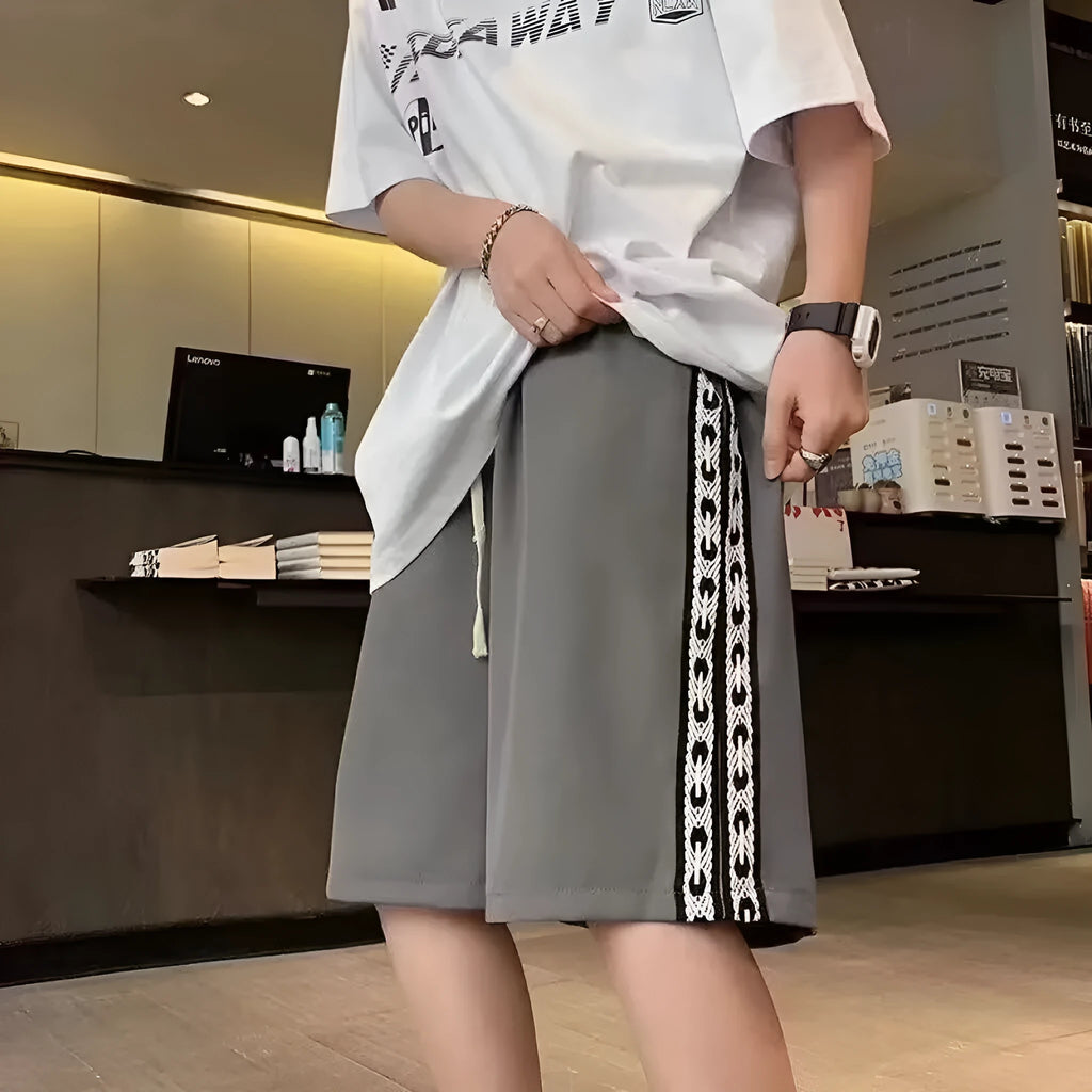 Man wearing loose-fit black track pants, showcasing the baggy sports style and elastic waist.