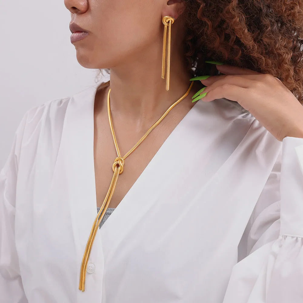 Gold titanium steel knotted tassel necklace and matching earrings set on white background